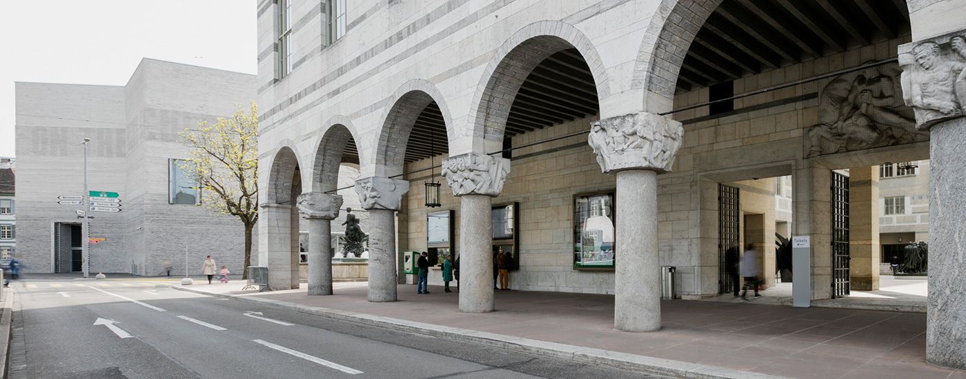 Wir sehen die Bögen der Front des Kunstmuseums Basel eine Strasse und im Hintergrund der Neubau des Kunstmuseums