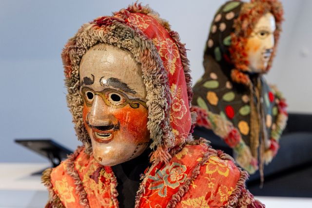 Two masks with red cheeks, in capes and hoods